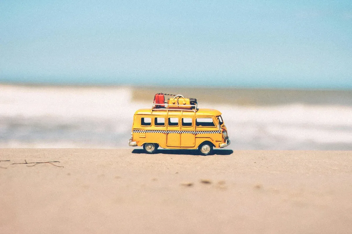 Yellow vintage van on beach with camping gear